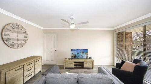 sala de estar con sofá y reloj en la pared en Fairhaven Retreat Accessible Accommodation, en Ettalong Beach