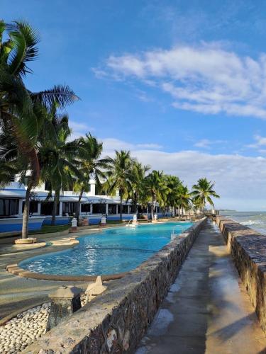 a swimming pool next to the ocean with palm trees at บ้านนาวาภิรมย์ ชะอํา in Ban Khlong Khot