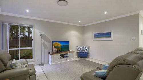 a living room with two couches and a tv at Ocean Beach Holiday House in Ettalong Beach