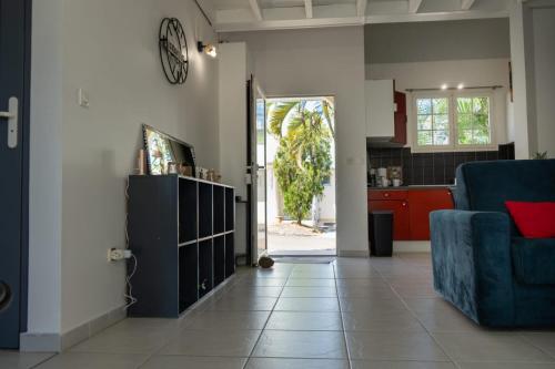 a living room with a blue couch and a kitchen at La Villa Noémie - Parking - Proche des Plages in Sainte-Anne