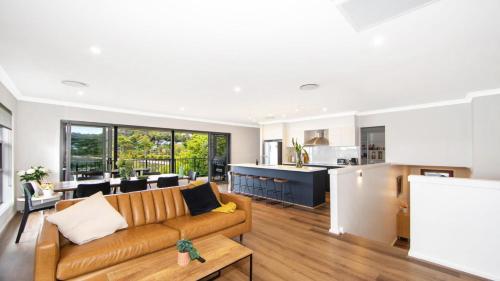 a living room with a couch and a kitchen at Bay Edge - Tascott in Point Clare