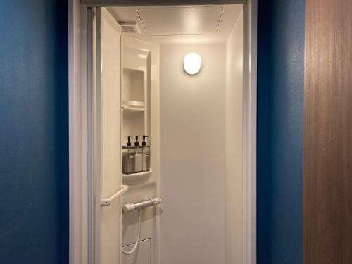 a white door with a refrigerator in a room at Hostel Lodging Tokyo Ueno in Tokyo