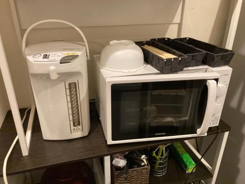 a microwave and a toaster oven on a shelf at Hostel Lodging Tokyo Ueno in Tokyo
