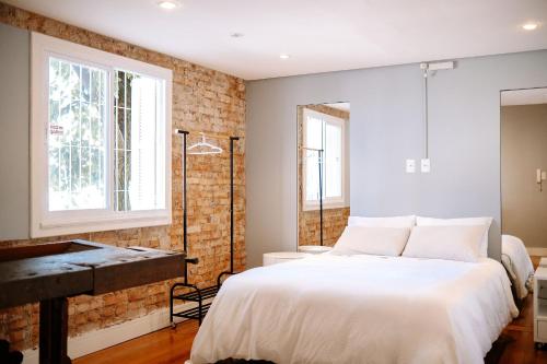 a bedroom with a bed and a brick wall at Prédio Histórico na Rio Branco in Caxias do Sul
