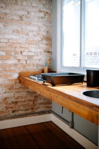 a kitchen with a counter with a sink and a brick wall at Prédio Histórico na Rio Branco in Caxias do Sul