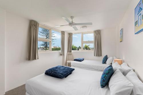 two beds in a room with two windows at 84 The Spit Holiday Apartments in Mooloolaba