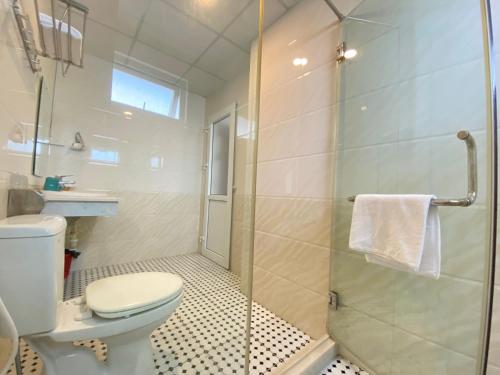 uma casa de banho com um WC e uma cabina de duche em vidro. em Hai Dang Hotel em Cửa Lò