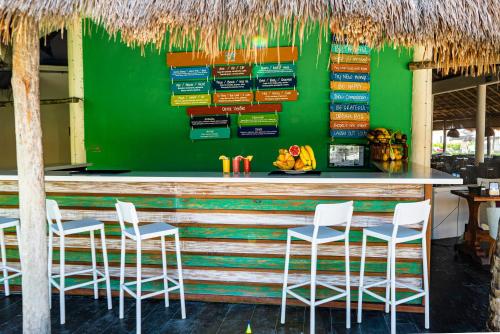 a green bar with white chairs and a green wall at Catalonia Yucatan Beach - All Inclusive in Puerto Aventuras