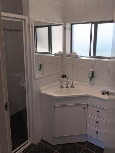 a white bathroom with a sink and a mirror at Arkana Motor Inn & Terrace Apartments in Mount Gambier
