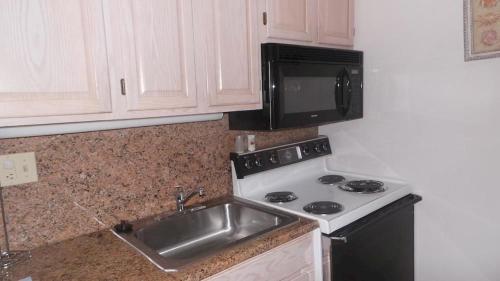 a kitchen with a sink and a stove and a microwave at Watson's Regency Suites in Ocean City