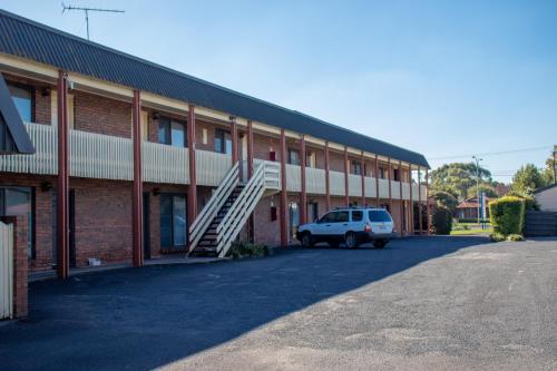 a white truck parked in front of a brick building at Arkana Motor Inn & Terrace Apartments in Mount Gambier