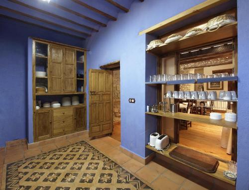 cocina con paredes azules y armarios de madera en Cortijo Palacete La Tala, en Guadix