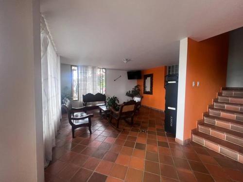 a living room with orange walls and a staircase at Espectacular casa de campo en finca cafetera in Moniquirá