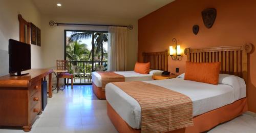 um quarto de hotel com duas camas e uma televisão em Catalonia Yucatan Beach - All Inclusive em Puerto Aventuras