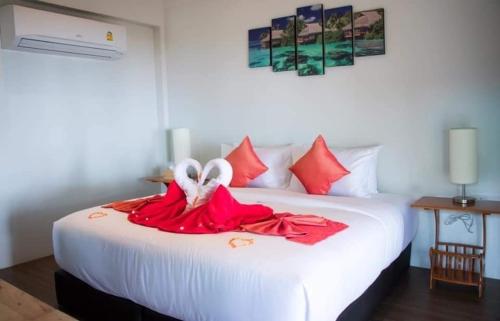 a white bed with red sheets and white shoes on it at Koh Jum Delight Beach in Ko Jum