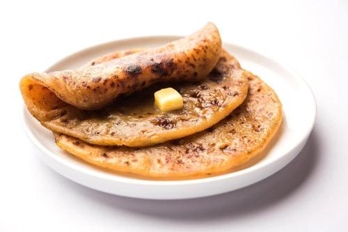 three pancakes with a pat of butter on a plate at Hotel Mandakini Palace in New Delhi