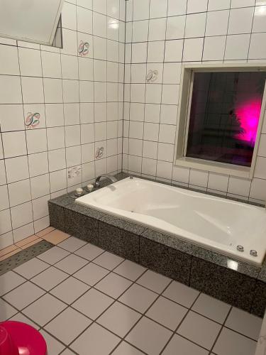 a bath tub in a bathroom with a window at HOTEL　LISBON in Maibara