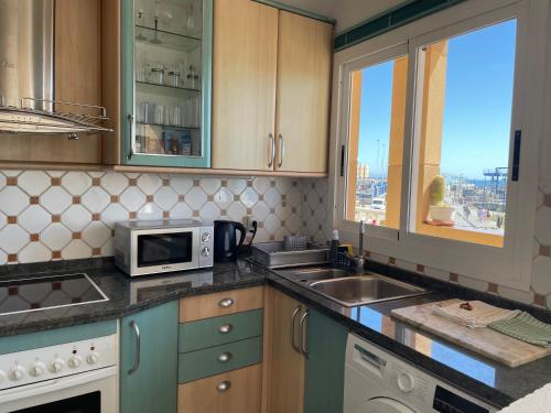 a kitchen with a microwave and a sink and a window at La Bocayna Vistas 3 Islas in Corralejo