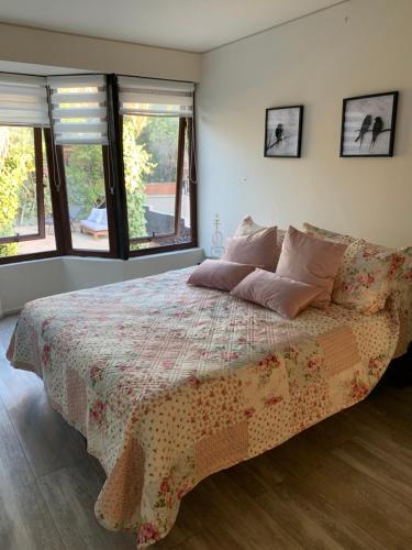 1 dormitorio con 1 cama con una manta de flores y ventanas en Agradable casa con piscina, cerca del mall., en Santiago