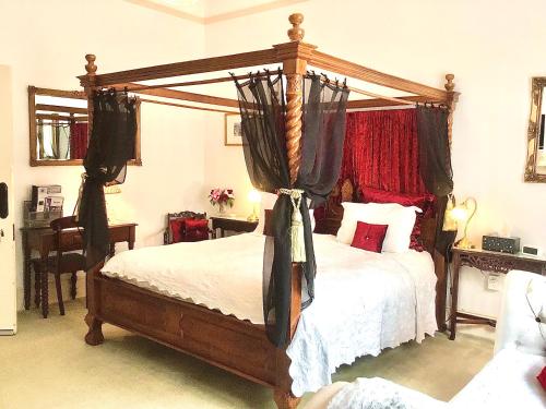 a bedroom with a wooden canopy bed with curtains at Kurrajong House in Launceston