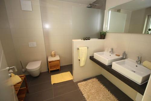 a bathroom with two sinks and a toilet and a mirror at Aquamarin Ostseetraumsuite 10 in Neuhaus