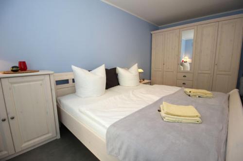 Un dormitorio con una cama blanca con toallas. en Aquamarin Ostseetraumsuite 01, en Neuhaus