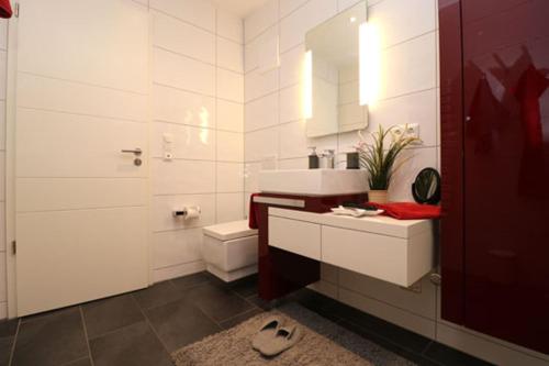 a white bathroom with a sink and a toilet at Residenz am Hafen Boddensuite in Ahrenshoop