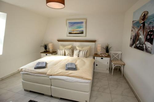 a white bedroom with a large bed and a desk at Aquamarin Ostseetraumsuite 12 in Neuhaus