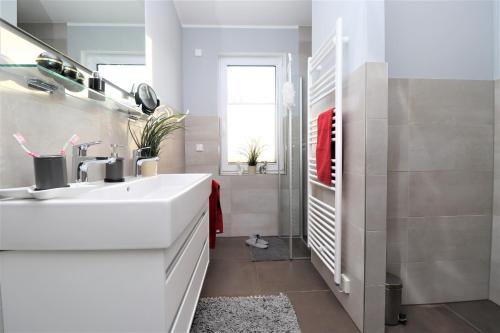 y baño con lavabo blanco y espejo. en Meerquartier App 08, en Neuhaus
