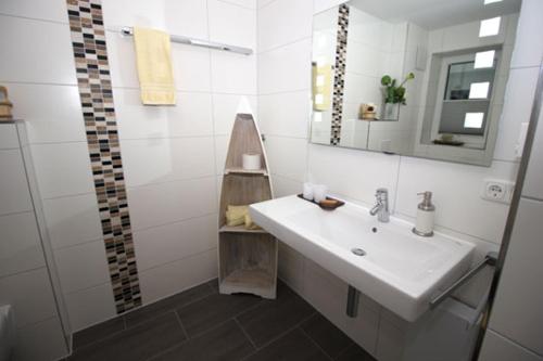 a white bathroom with a sink and a mirror at Aquamarin Ostseetraumsuite 02 in Neuhaus