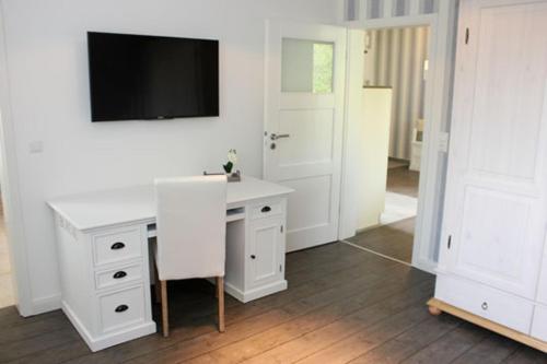 a room with a white desk and a tv on a wall at Haus Ostseeidyll, App 01 in Neuhaus