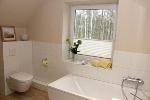 a bathroom with a toilet and a tub and a window at Strandvilla Birkenallee Haus Sommerlicht in Neuhaus