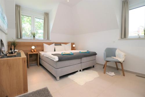 a bedroom with a bed and a chair and a television at Ferienhäuser Villa Ostseekind in Neuhaus