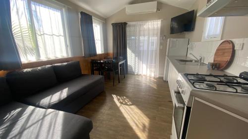 a living room with a couch and a kitchen with a stove at Twin Dolphins Holiday Park in Tuncurry