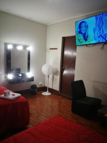 Habitación con cama, silla y TV de pantalla plana. en una habitacion amplia para disfrutar en Lima