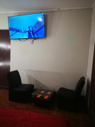 Habitación con 2 sillas y TV en la pared. en una habitacion amplia para disfrutar en Lima