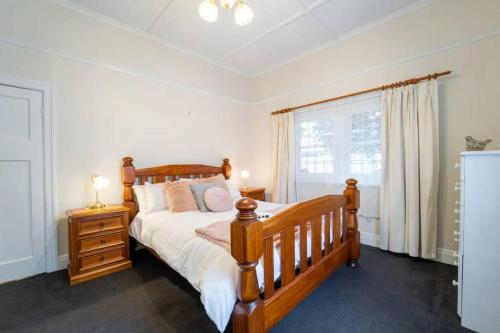 een slaapkamer met een houten bed en een raam bij Cambridge House, Bendigo in Bendigo