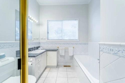 a white bathroom with a tub and a toilet and a sink at Cambridge House, Bendigo in Bendigo