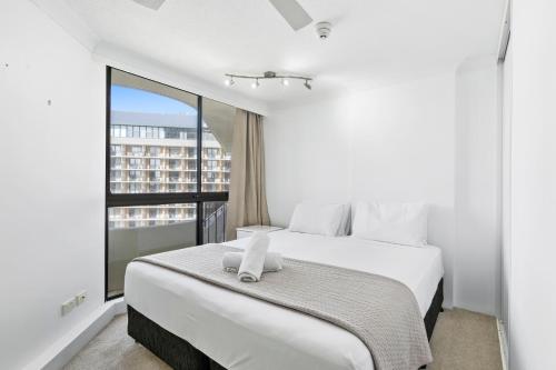 een slaapkamer met een groot wit bed en een raam bij Cosmopolitan - Hosted by Coastal Letting in Gold Coast