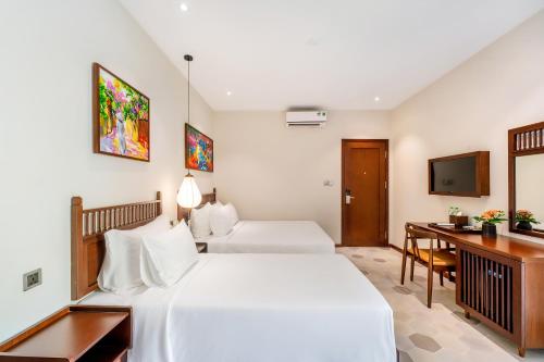 a bedroom with two beds and a desk and a television at Chillax Old Town Villa in Hoi An