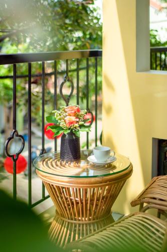a table with a cup and flowers on a balcony at Chillax Old Town Villa in Hoi An