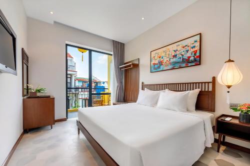 a bedroom with a large white bed and a window at Chillax Old Town Villa in Hoi An