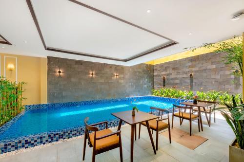 a pool in the middle of a restaurant with tables and chairs at Chillax Old Town Villa in Hoi An