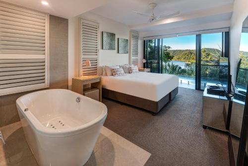 um quarto com uma banheira, uma cama e uma televisão em North Cape 5 on Hamilton Island by HIHA em Hamilton Island