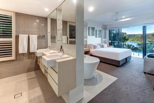 a bathroom with two sinks and a tub and a bed at North Cape 5 on Hamilton Island by HIHA in Hamilton Island