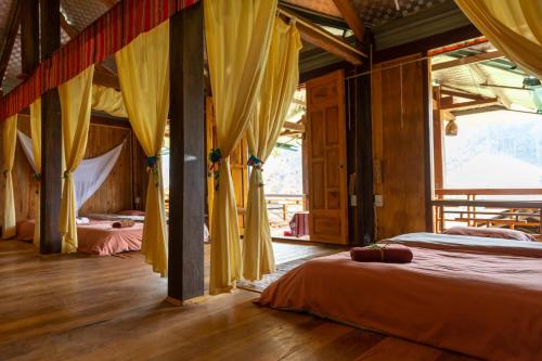 a bedroom with two beds with yellow drapes at Truong Nhan Tram Tau Homestay in Cham Ta Lao