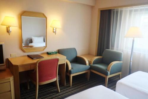 a hotel room with a desk and chairs and a mirror at Santos Hotel in Taipei