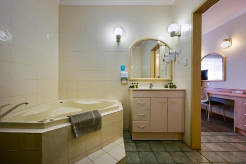 a bathroom with a tub and a sink and a mirror at Westland Hotel Motel in Whyalla