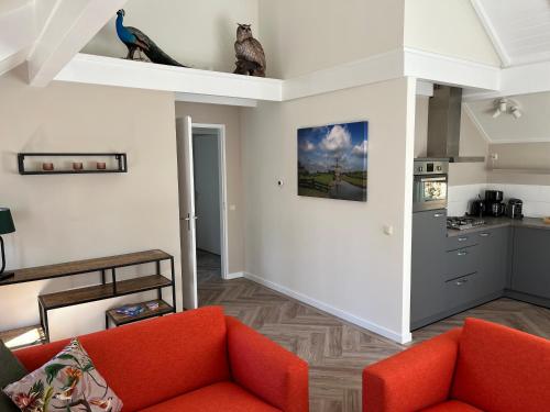 a living room with an orange couch and a kitchen at Villa Victoria with sauna in Ermelo in Ermelo