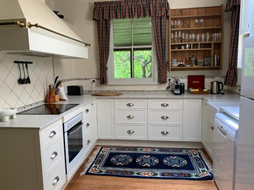 una cocina con armarios blancos y una alfombra en el suelo en Capers Cottage and Barn Accommodation, en Wollombi